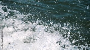 Water splashing in slow motion from a boat making its way on a lake.