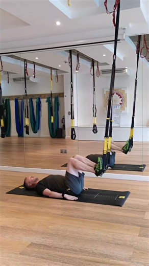 The TRX HIP PRESS has got to be one of the best ground facing exercises in the TRX exercise library. The posteror chain is working off the charts and leaves you feeling great after. Strap - Mid Calf Ground facing anchor point. Start with your heels in the foot cradles and knees stacked above your hips. Drive your glutes straight up, pause and return to the start. To add a slight progression you can raise your arms towards the sky to reduce your stability. #trxlowerbody #trxhippress | Anthony May
