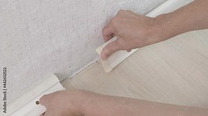 4k. The craftsman puts a decorative end cap on the plastic baseboard - installation of floor coverings. Technology installation and installation of plastic floor plinth. Room renovations at house