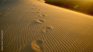 Desertscape of Dune of Pilat at sunset. A row of footprints on golden desert