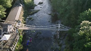 Whitewater kayakers navigate rapids at chain bridge over the River Dee near Llangollen North Wales