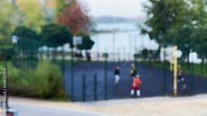 Blurred background basketball training on a sports field in a city park near trees and water