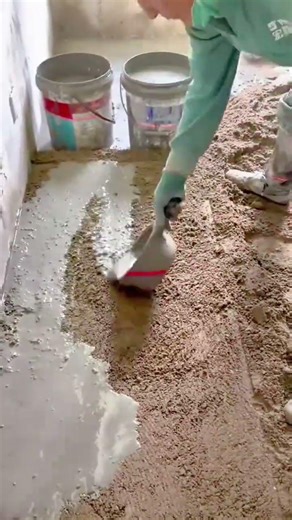 vibrating a large white ceramic floor tile using a handheld machine to ensure a level installation