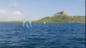 Small sailboat sailing across the ocean in front of Tafelberg mountain on the Caribbean island of Curacao. Stock Video