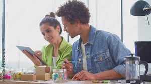 Couple with digital tablet running online candle store from home writing labels for packaging and shipping - shot in slow motion