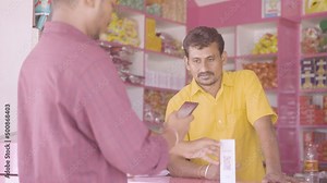 handheld shot of customer paying money after trying to pay not working using QR code scanner at kirana store - concept of technical or internet issue during payement.
