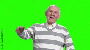 Grandpa laughing at nonesense, slow-motion. Old man laughing because of hogwash against green background.