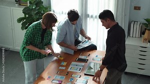 Top view of smart Ui designer brainstorming and planning about Ux Uo design or mobile interface wireframe design with diverse develop team. Caucasian programer walking and joining meeting.Convocation.