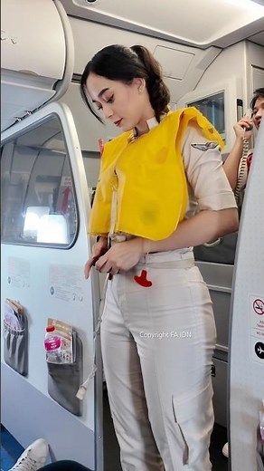 Flight attendant demonstrates how to use a life jacket