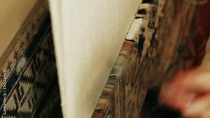 Carpet weaving. Turkish woman weaving a carpet with peace of genuine camel wool with a manual waving machine. Needlework. Carpet-makers work close-up video.