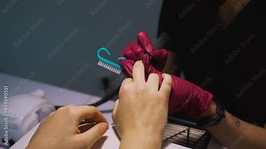 The manicurist makes a hardware manicure and cuts the cuticle with an electric milling cutter with a diamond nozzle flame with a sharp end and a red line on the middle finger of right hand of client