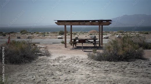 View the campground area at Salton Sea Recreation Area with signs, picnic tables, and dry landscape under the sun