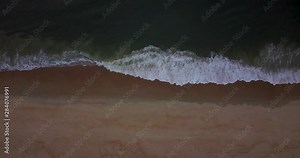 Waves crashing on beach top to bottom from drone directly overhead.