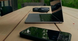 A laptop and a cell phone sitting on a wooden table