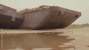 Rusting Barges Stranded on Muddy Shoreline: Abandoned Industrial Relics by the Water. Themes of industrial decline, environmental wear, and resilience of nature are visually prominent in this imagery.