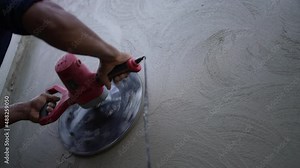 A construction worker is working using an automatic plastering machine to plaster the walls, use of modern technology and electric tools in construction work