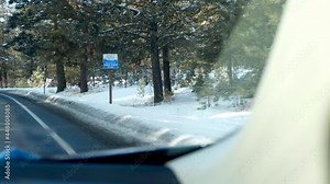 Watching the passing snow lined road and forests in the winter from a moving car in rural countryside and town of McCall, Idaho