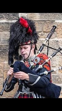 A Scottish Piper Man in Kilt Playing Bagpipes Busking in London Big Ben