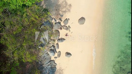 Aerial top view on woman in swimsuit relaxing and sunbathing on beach white sand near the sea. Attractive brunette girl in bikini laying on a sandy coast.