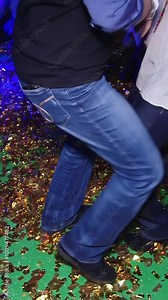 Amidst a lively celebration, a group of friends showcases their humorous dance moves, reveling in the joyful atmosphere. The colorful, glittering floor adds to the festive vibe of the party.