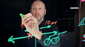 The concept of online education and distance learning. A math teacher writes a formula on a glass marker board