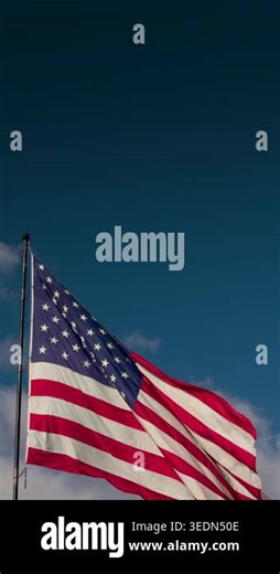 A slow motion vertical seamless looping shot of an American flag waving in the wind against a blue sky with clouds and open copy space. This patriotic United States flag footage is ideal for vertical video backgrounds, social media, mobile formats Stock Video Footage - Alamy