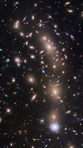 The gravity from these galaxies is strong enough to bend light. Known as MACS J0416.1-2403 (say that three times fast!), this cluster of galaxies weighs as much as a million billion Suns! Its gravity is so powerful that it bends, magnifies, and brightens the light from objects far behind it in a phenomenon called gravitational lensing, seen as the warped objects throughout this cluster. MACS J0416.1-2403 is located about four billion light-years away. Music credit: “Faint Blue” by Ronnie W Verbo