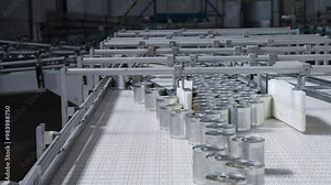 Cans moving on a conveyor belt in a food production line, featuring automation, packaging, sealing, and quality control in an industrial setting. Factory, manufacturing, and production footage