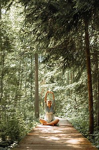 Young woman sitting in lotus position and doing breathing exercises...