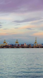 vertical timelapse of  deep sea port with cargoship loading and unloading with many cargo containers,import and export freight transportation by container ship