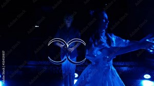 Light LED dance show. Impressive dances of two beautiful girls in dresses with flashlights glowing with LEDs in their hands and a guy with LED knives