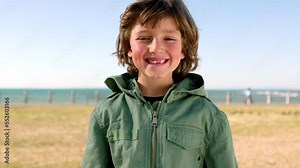 Happy, smile and face of child at the beach having fun while on summer vacation for travel. Happiness, excited and cute young boy smiling by the ocean while on holiday, adventure or trip in Australia