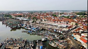 The hustle and bustle at the largest fish port in Java is filled with traditional boats lining the docks, juxtaposed to the industrial fishery area and densely populated village. Aerial drone footage