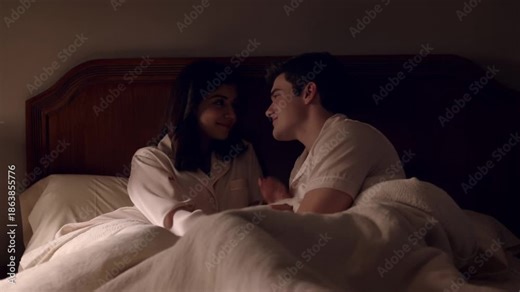 Intimate moment of a couple in bed, sharing a tender and loving connection in the bedroom setting. The low lighting emphasizes the close bond between the two individuals Stock Video