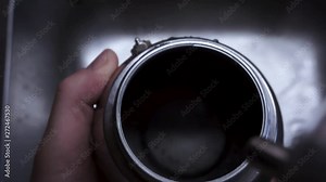 Placing a metal filter with coffee grounds into the metal kettle to brew