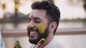 Woman Applying Turmeric On Groom's Face During Haldi Ceremony - close up