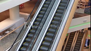 Escalator in a large multi-storey shopping center. High angle view. Going up and down an escalator with glass walls and metal steps in a sparsely populated business center.