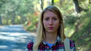 clip-1019810911-portrait-traveler-woman-hitchhiking-on-forest-road
