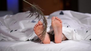 close up of tickling baby child feet sticking out from under blanket.