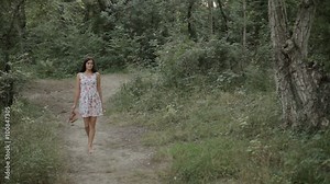 Beautiful girl in the dress walking along a path in the woods