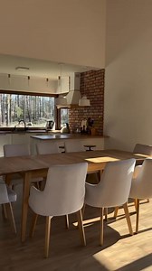 This classic modern kitchen combines the elegance of traditional design with a warm contemporary touch. The dominance of natural wood tones on the cabinets and floors gives a warm and organic feel, while classic details such as soft carvings and gold doorknobs add an elegant impression. Large glass windows take center stage, bringing in abundant natural light and directly connecting the kitchen to the natural scenery outside, creating a fresh and calm atmosphere that blends in with the surroundi