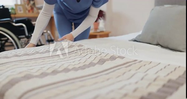 Medical nurse, hands and making bed, cleaning and person in housekeeping service for retirement home. Professional caregiver, tidy and housework of staff in bedroom for healthcare, hygiene or prepare