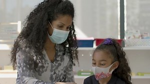 Pandemic Learning. Teacher runs a lesson with a young student in a Mask. Children in masks as they come back to their new learning environment. Shot in 4k.