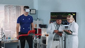 Fit athlete in VR glasses walking on treadmill in sports lab while two doctors discussing his EKG data.