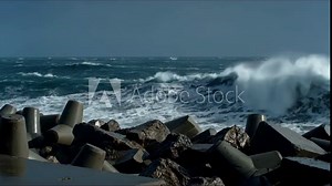 Dynamic video of powerful ocean waves crashing against concrete sea defense blocks and rocks, showing the force of nature in storm weather footage.
