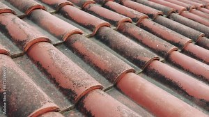 Closeup of red tiles on roof of old house. Video captures texture and detail of each tile, highlighting wear and weathering. Tiles form intricate pattern, showcasing traditional roofing techniques