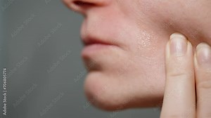 A woman uses a wax strip to remove hair from her mustache area; she swiftly pulls it, extracting the hair, in slow-motion, macro view.