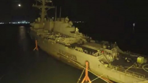 USS John McCain, damaged in a collision that left 10 sailors dead, is lifted from water prior to repairs