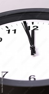 4K footage vertical video front view CU black wall clock is telling the time before noon.