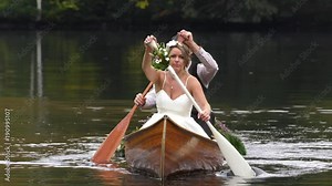 bride and groom paddling canoe on lake front angle 4k